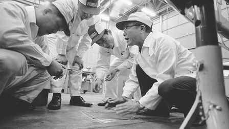 Soichiro Honda a pracovníci v továrně v bílých kombinézách