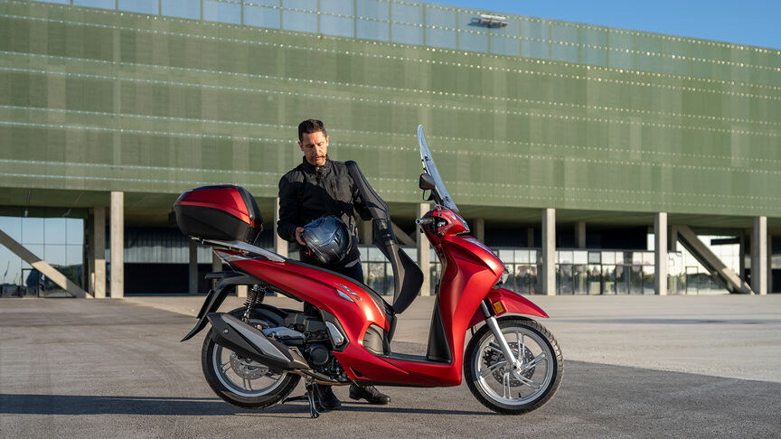 Honda SH350i, pravý přední poloprofil, s jezdcem, na silnici, červený motocykl