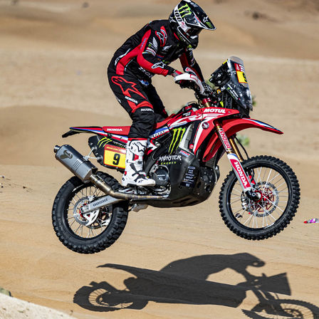 Jezdec rallye Dakar na motocyklu Honda v poušti.